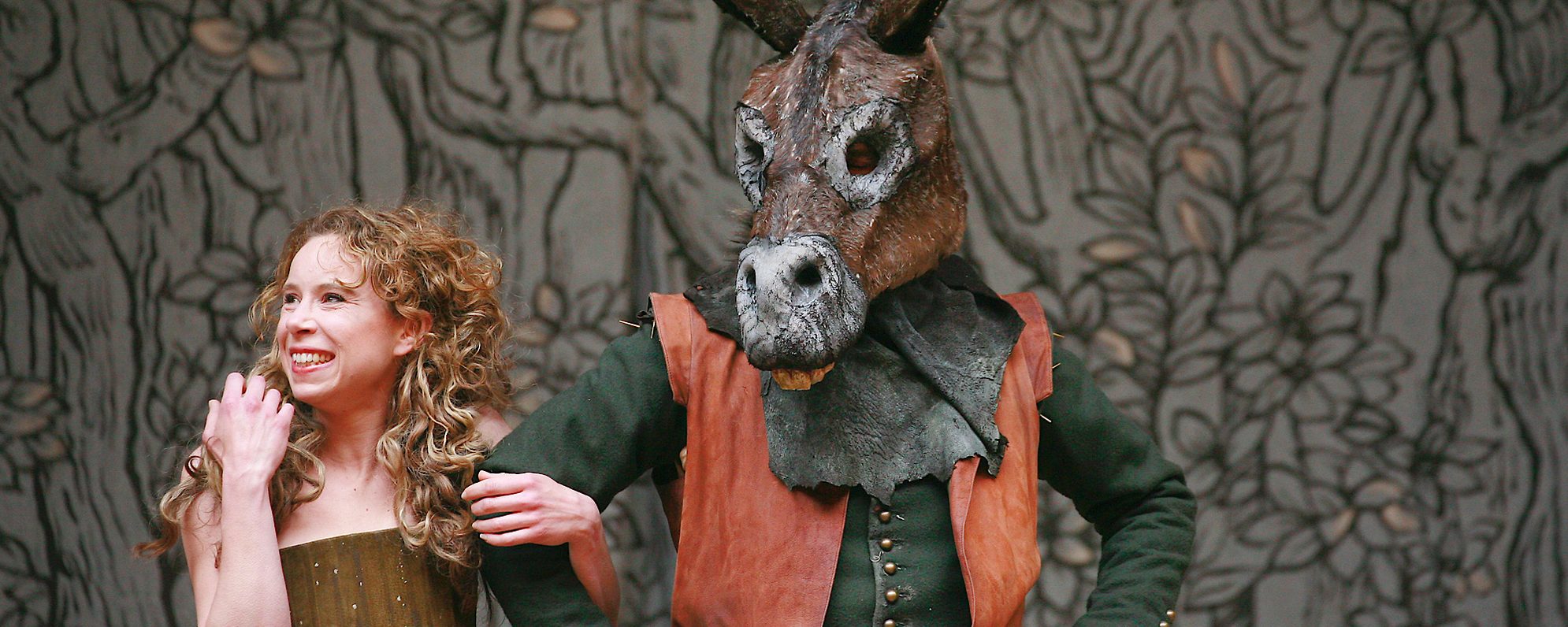 Discover Plays A Midsummer Night’s Dream 2013 An actor smiles and holds the arm of another actor who wears an ass’ head